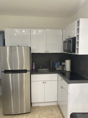 A modern kitchen with stainless steel appliances, white cabinets, and a black countertop.