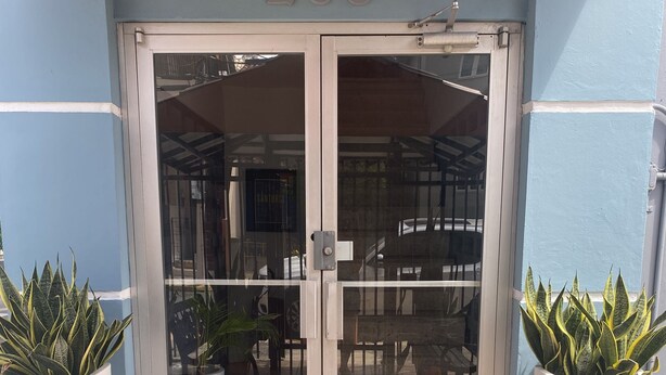 A building entrance with a glass door, number 266, potted plants, and a tiled floor.