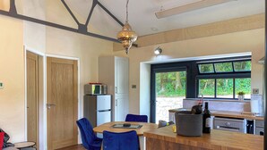 Une cuisine moderne avec un îlot central en bois, des chaises bleues, un four à micro-ondes et un réfrigérateur.