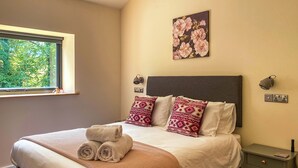 Un lit bien fait, avec des serviettes pliées, un plaid à motifs et deux coussins décoratifs.