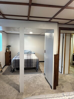 A bedroom with a bed, a nightstand, a lamp, and a wardrobe.