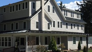 A two-story building with a prominent gable roof and a front porch. - The Frogtown Inn (Canadensis)