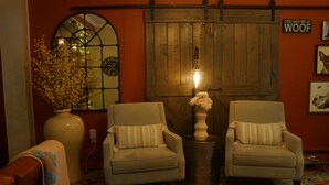 A cozy room with two armchairs, a large vase with flowers, a wall clock, and a wooden door. - The Frogtown Inn (Canadensis)