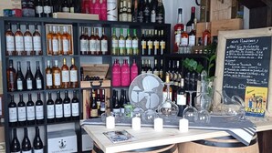 Een wijnwinkel met schappen vol verschillende wijnflessen, een krijtbordmenu en houten vaten.