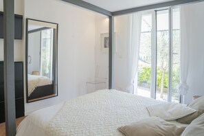 Ein Schlafzimmer mit einem großen Bett, einem Spiegel und einem Fenster mit Vorhängen.