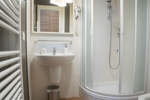 Ein Badezimmer mit Waschbecken, Spiegel, Fön und Dusche.