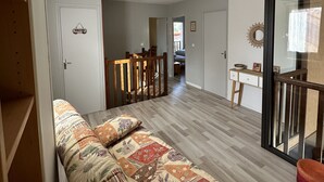 A modern living room with a sofa, wooden flooring, a dining area with chairs, and a glass door leading to another room. - Maison Familiale, South Aveyron 5minutes from St Rome de Tarn beach  (Saint-Rome-de-Tarn)