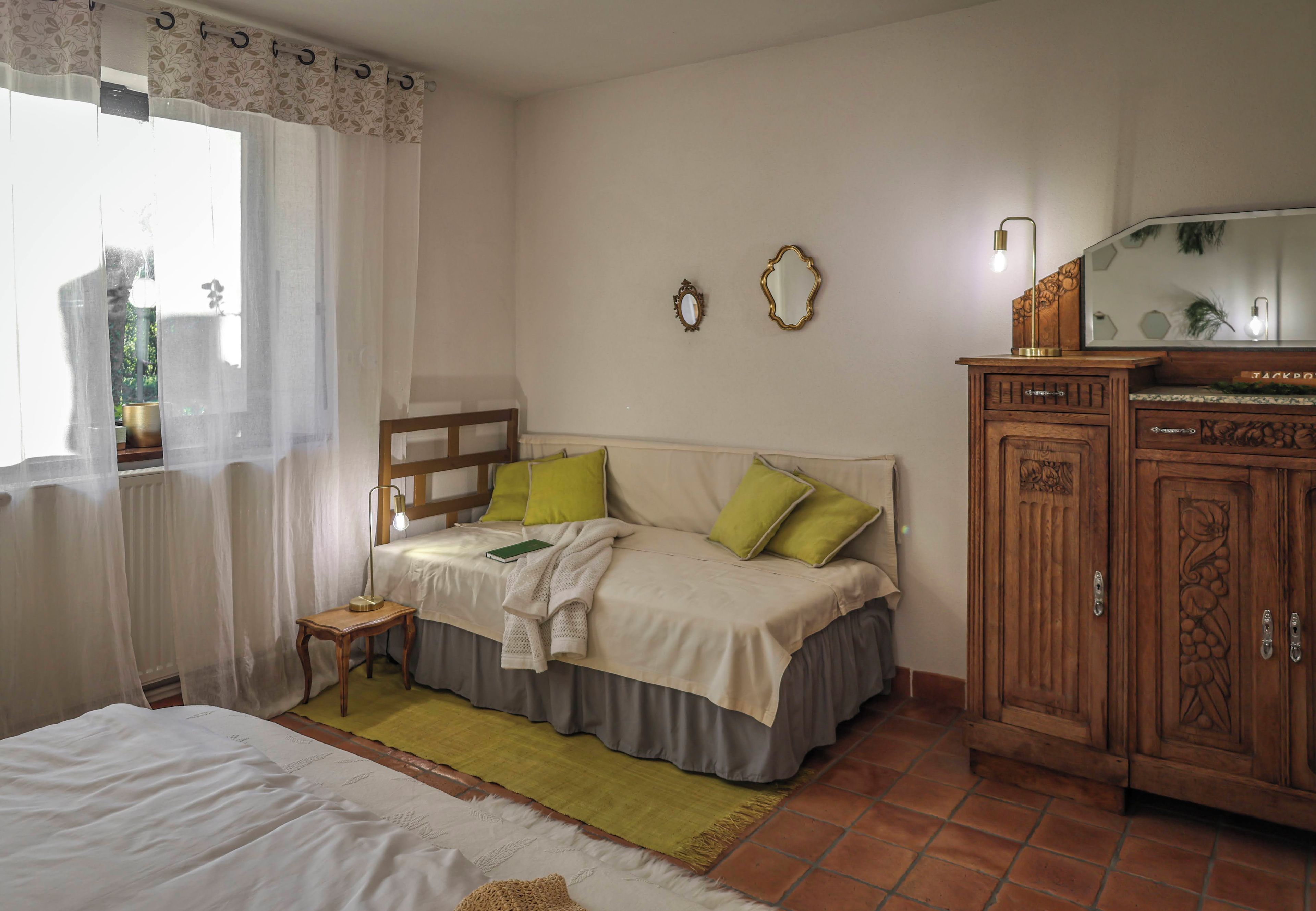Ein Schlafzimmer mit Bett, Nachttisch, Lampe, Kommode und zwei Wandspiegeln.