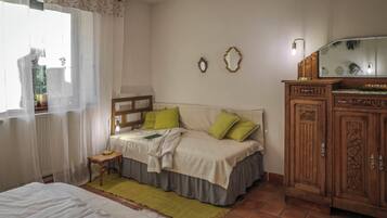 Ein Schlafzimmer mit Bett, Nachttisch, Lampe, Kommode und zwei Wandspiegeln.