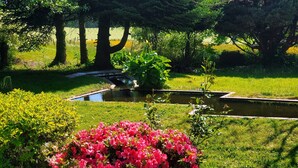 A garden with a pond, surrounded by lush greenery and flowering plants. - La Lande Cottage – 105 m² on one level, no stairs – Périgord Vert, Dordogne (Firbeix)