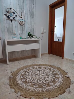 Une pièce avec une console blanche, un élément décoratif mural, une porte en bois et un tapis à motifs.