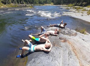 Een groep mensen ontspant aan een rivier met rotsachtige oevers.