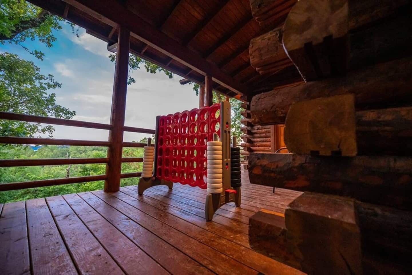 A wooden deck with a red exercise equipment, a stone wall, and a view of greenery.