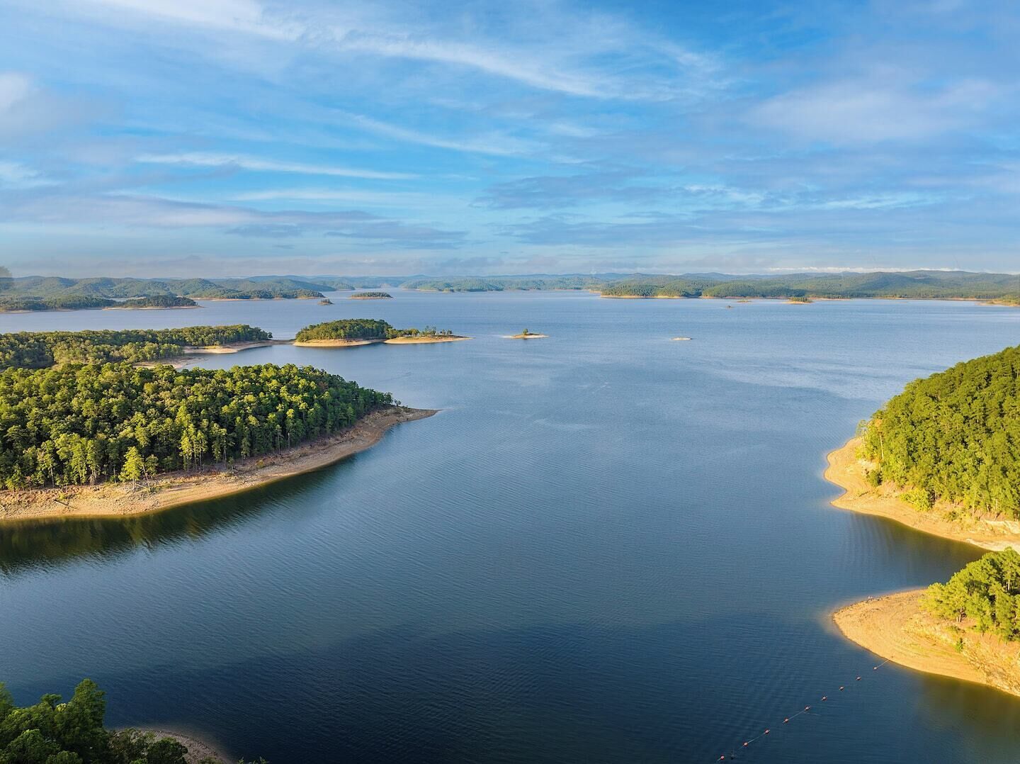 A large body of water with several islands, surrounded by dense forests.