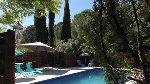 A swimming pool with lounge chairs and umbrellas, surrounded by tall trees and a wooden fence. - Agréable Chambre Indépendante Avec Piscine & Parc (Brézilhac)