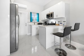 Een moderne keuken met een koelkast, magnetron en een kookeiland met barstoelen.