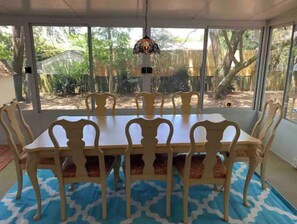 Enjoy meals in this dining area with a large table and six chairs, surrounded by windows offering a view of the outdoors.
