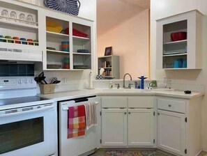 Compact kitchen with stove, sink, and ample storage.