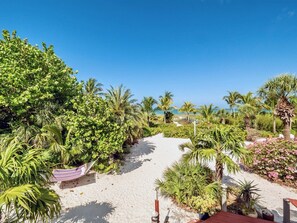 A pathway leading to a beach with palm trees and a hammock. - Bali Hi Estate (Captiva)