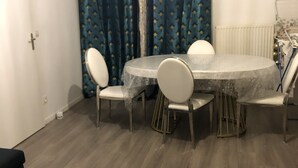 A dining area with a round table and four chairs, a blue rug, and a white sofa. - Chambre Simple Privée -saint Priest (Saint-Priest)