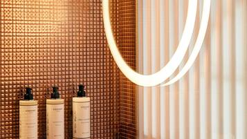 Un baño con pared texturizada, un espejo y tres botellas de productos para el cabello CODAGE Paris.