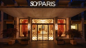 The entrance of a hotel with a modern design, featuring a prominent sign above the entrance and a series of arches leading into the building. - SO/ Paris Hotel (Paris)