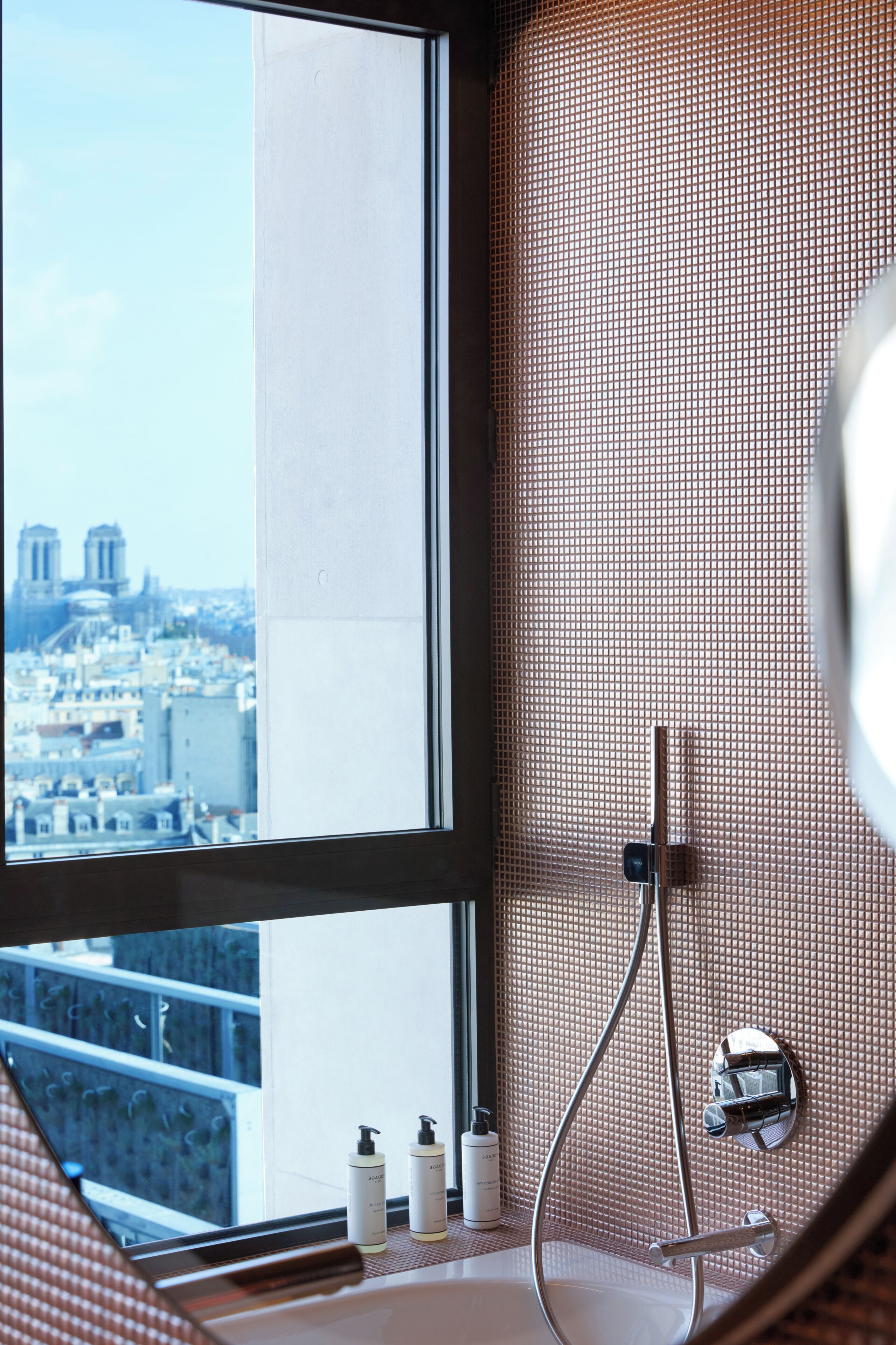 A bathroom with a bathtub, a shower, and a window overlooking a cityscape.