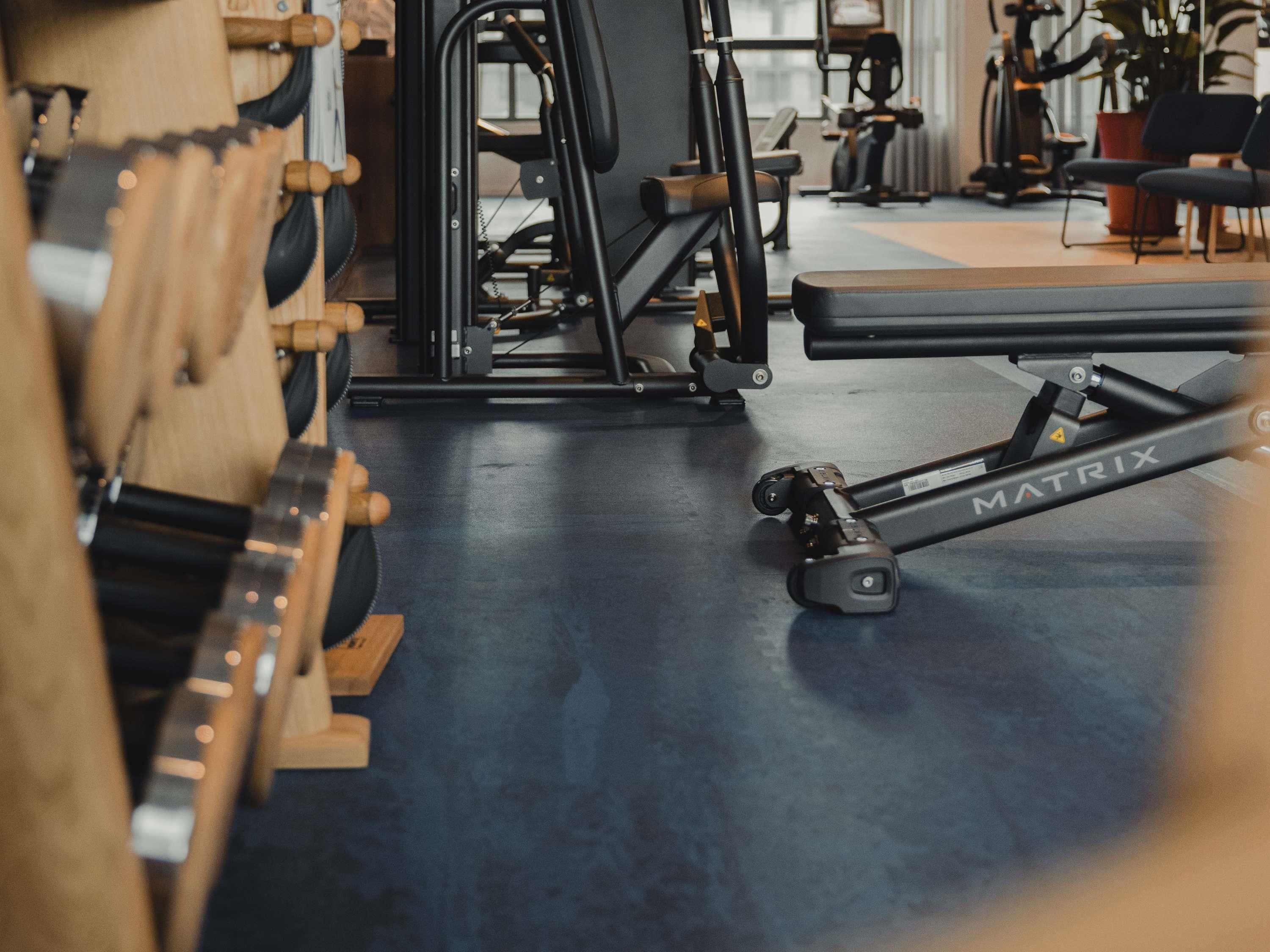Une salle de sport équipée de matériel d’exercice, notamment un rameur et un banc de musculation.