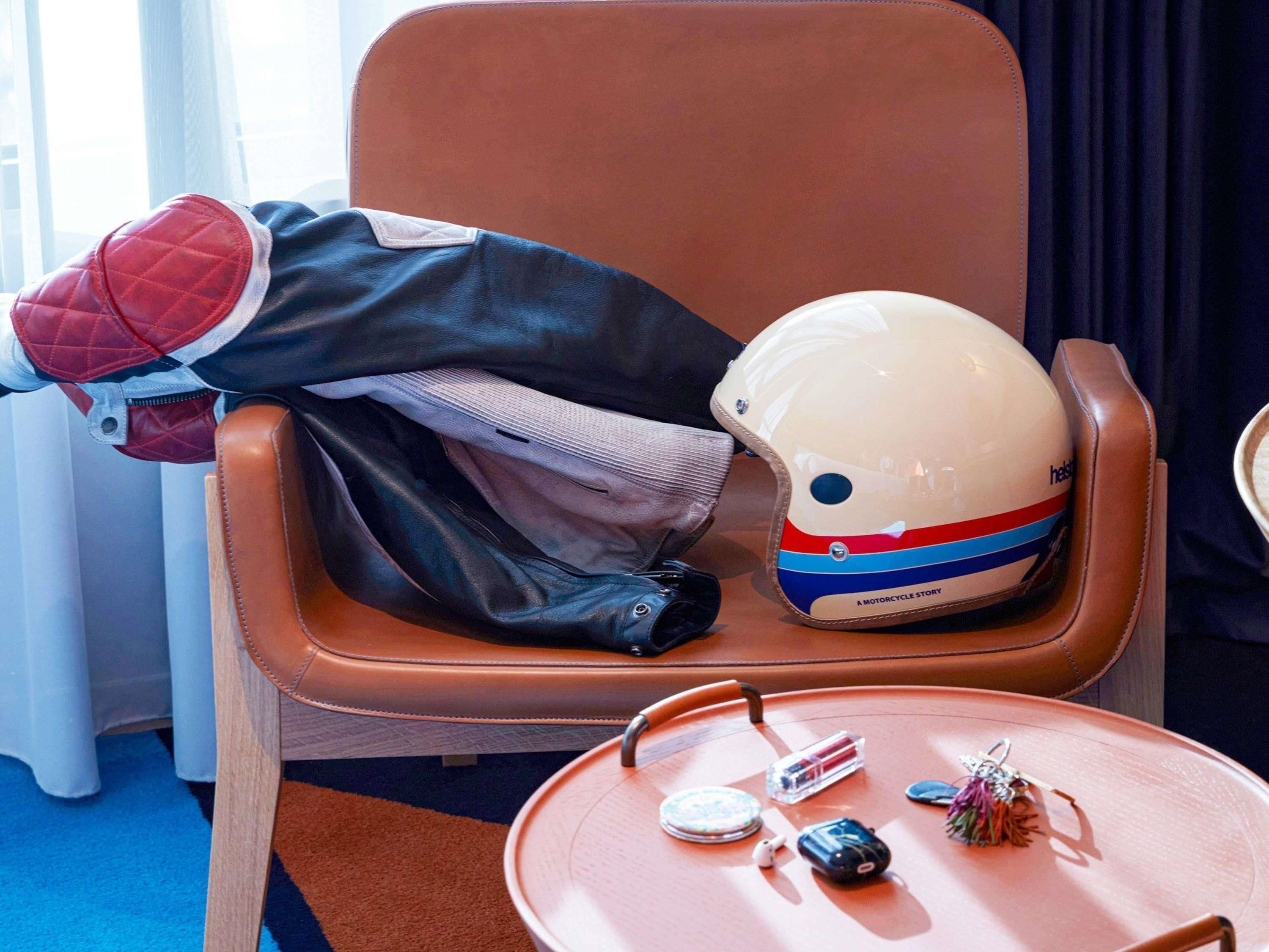 Una poltrona in pelle marrone con un casco e una giacca appoggiati sopra.