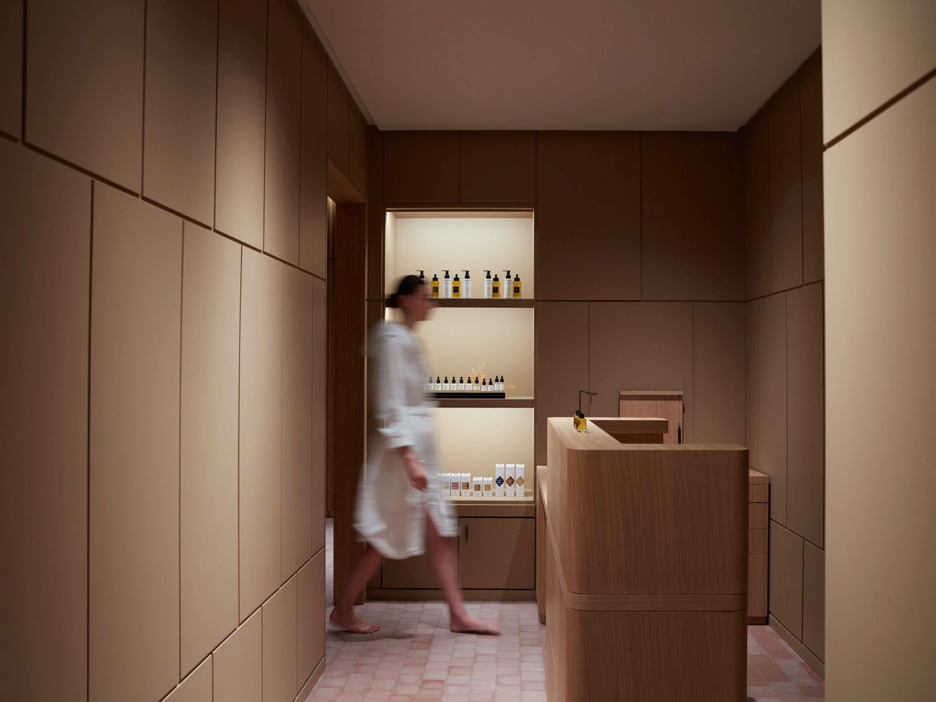 A modern bathroom with wooden paneling, a vanity with a sink, and shelves with toiletries.
