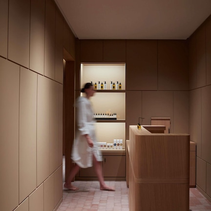 A modern bathroom with wooden paneling, a vanity with a sink, and shelves with toiletries.