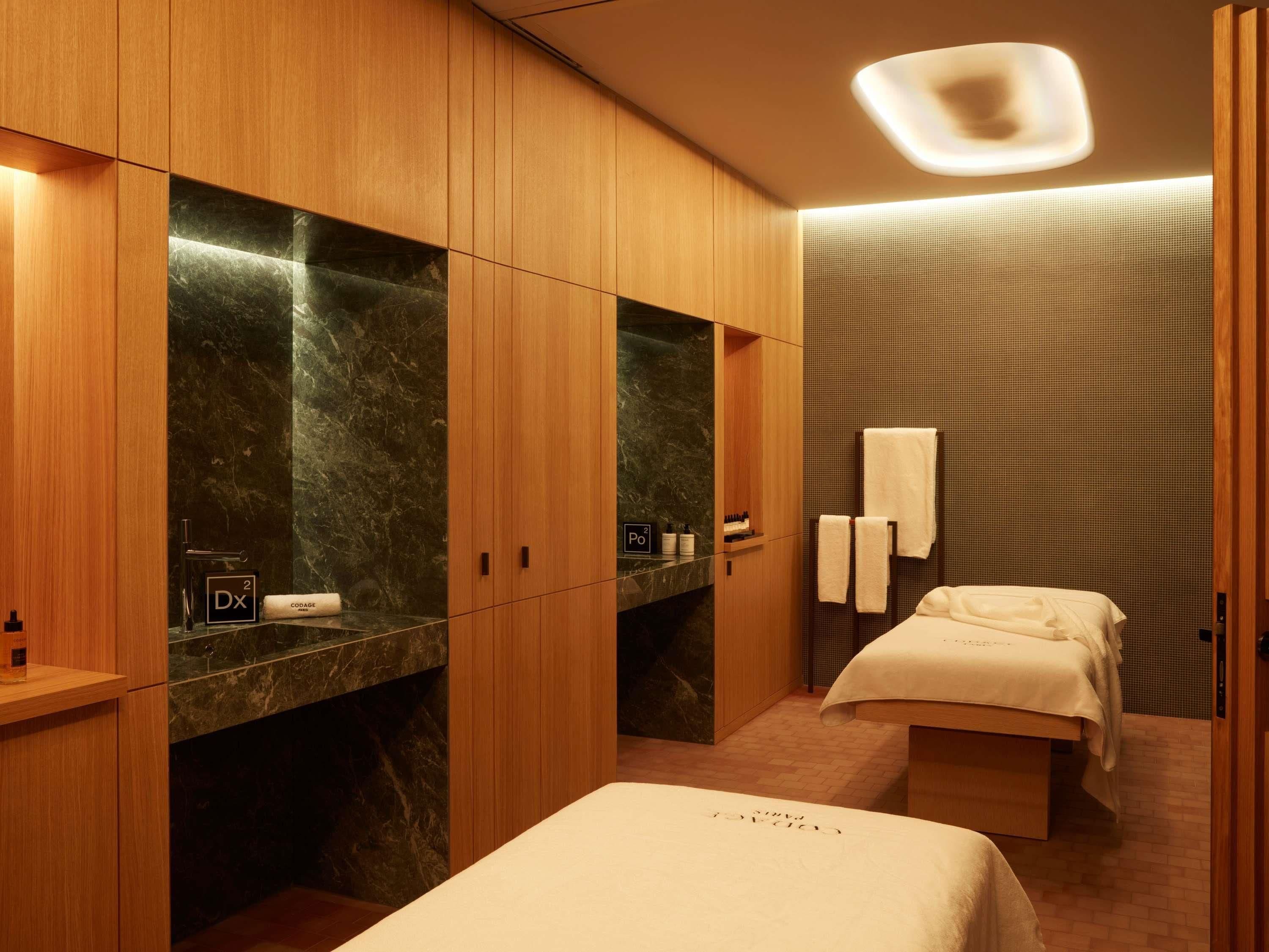 A modern bathroom with wooden cabinetry, marble countertops, a built-in shower, and a bed with a towel.
