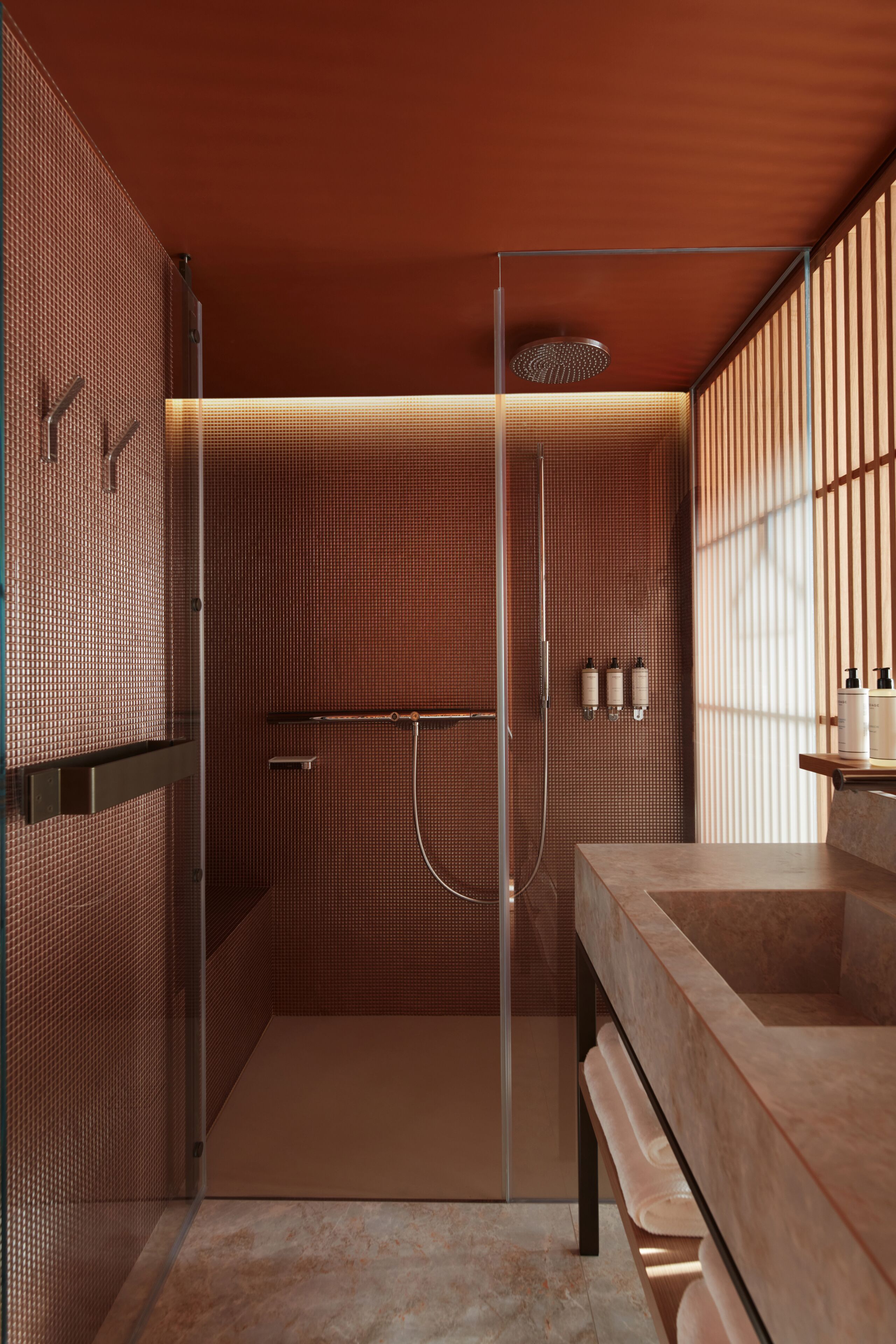 A modern bathroom with a glass-enclosed shower, a marble sink, and a towel rack.
