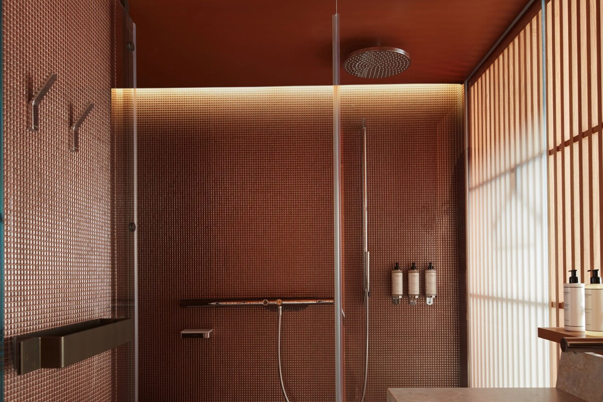 A modern bathroom with a glass-enclosed shower, a marble sink, and a towel rack.