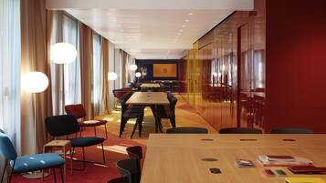 A conference room with a long table, chairs, and a projector screen.