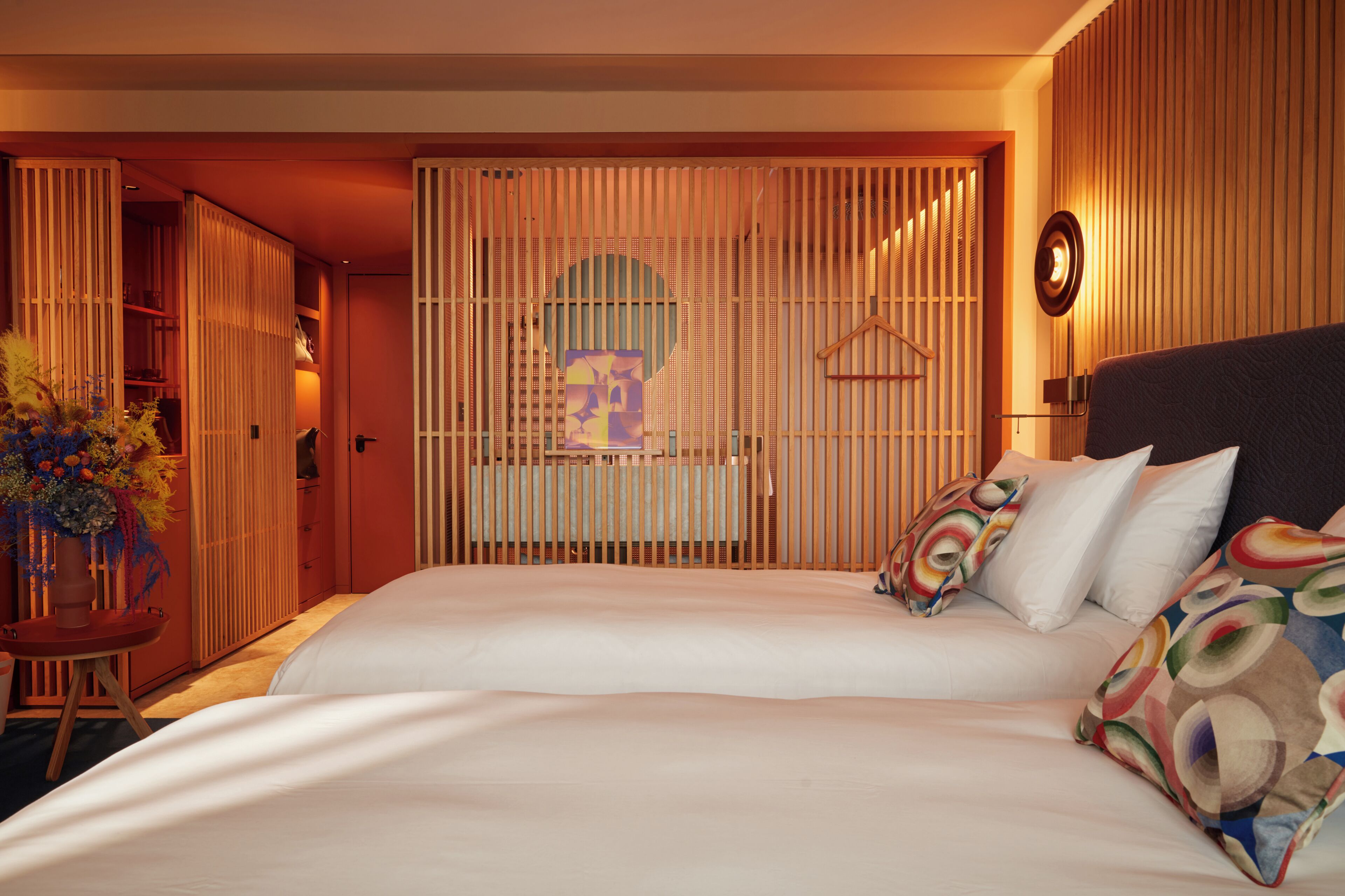 A hotel room with a large bed, a wooden partition, and a hanging light fixture.