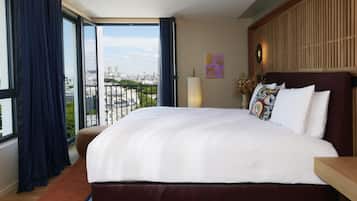 Habitación de hotel con una cama grande, vistas a la ciudad y un balcón.