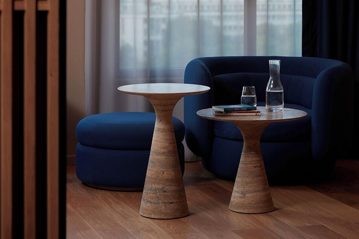 A modern room with two blue sofas, a wooden coffee table, and a glass table.