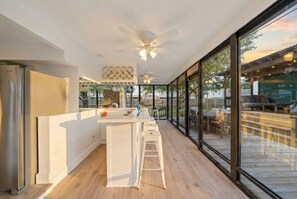 A modern kitchen with a central island, large windows, and a ceiling fan. - Cozy Home Near Kemah Boardwalk with Game Room (Kemah Area)