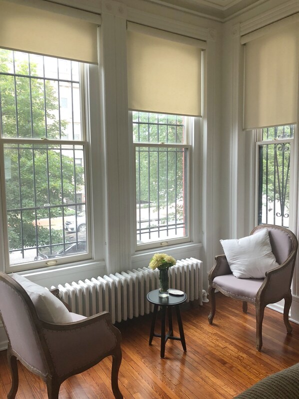 Relax in this classic room with a view, featuring a radiator, two comfortable chairs, and a small table with a vase of flowers.