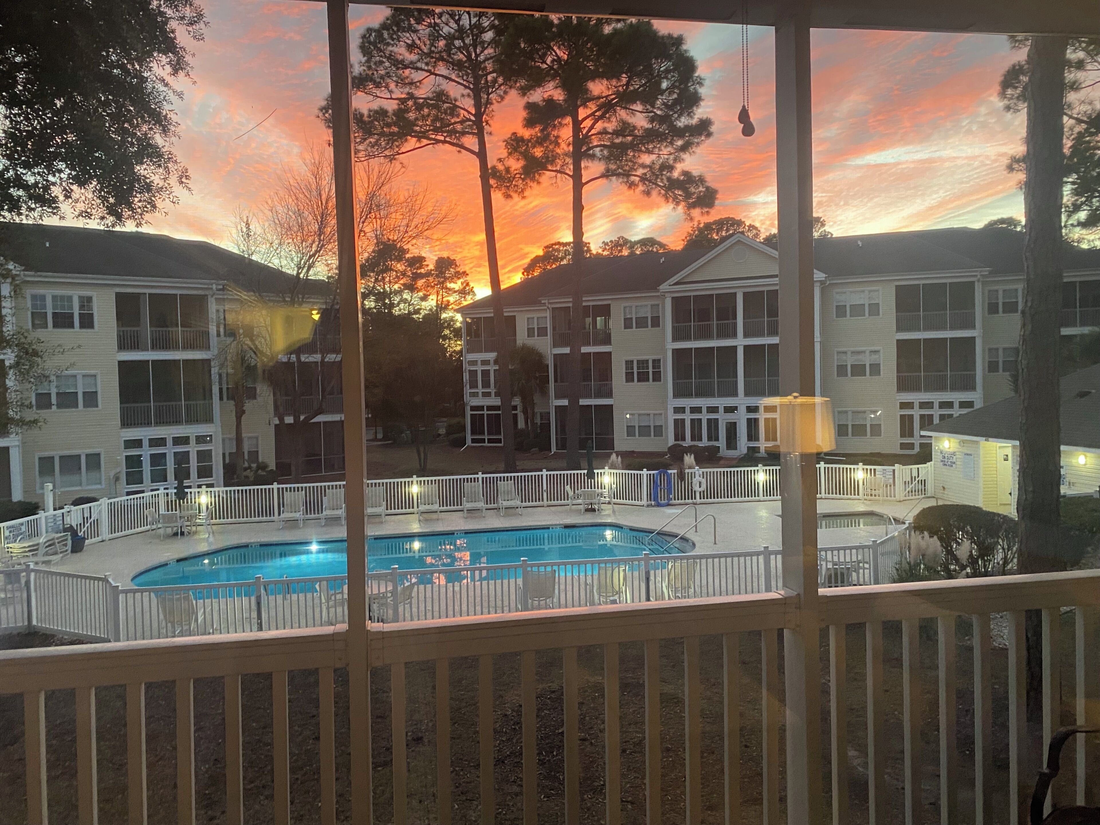 A pool area with a view of residential buildings and a sunset.
