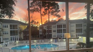 A pool area with a view of residential buildings and a sunset. - Ocean Keyes 3 BR Condo, XL balcony, pool, 1 block to beach, food,  & famous OD (North Myrtle Beach)