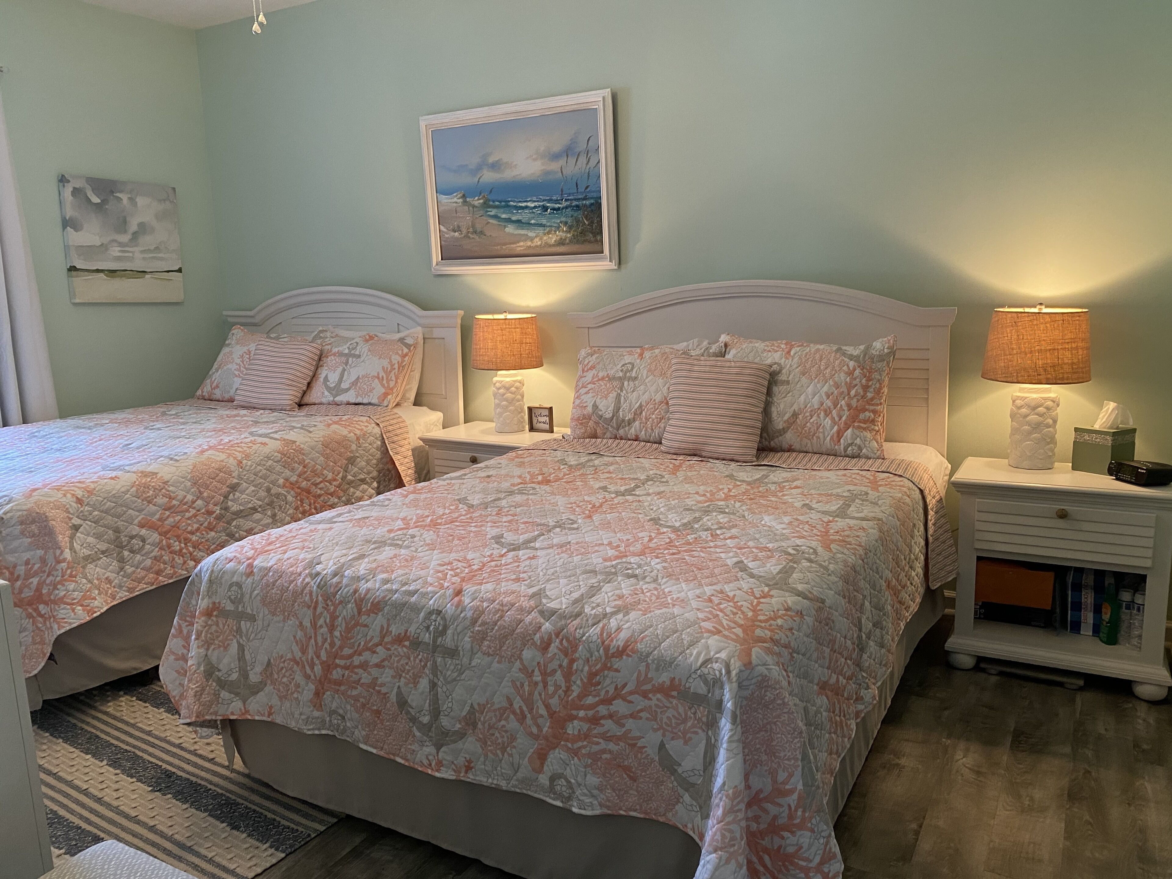 A bedroom with two beds, each with matching floral bedding and nightstands with lamps.