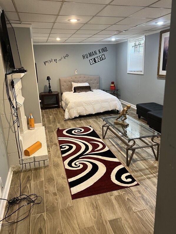 A modern bedroom with a bed, bedside table, lamp, and a motivational quote on the wall.