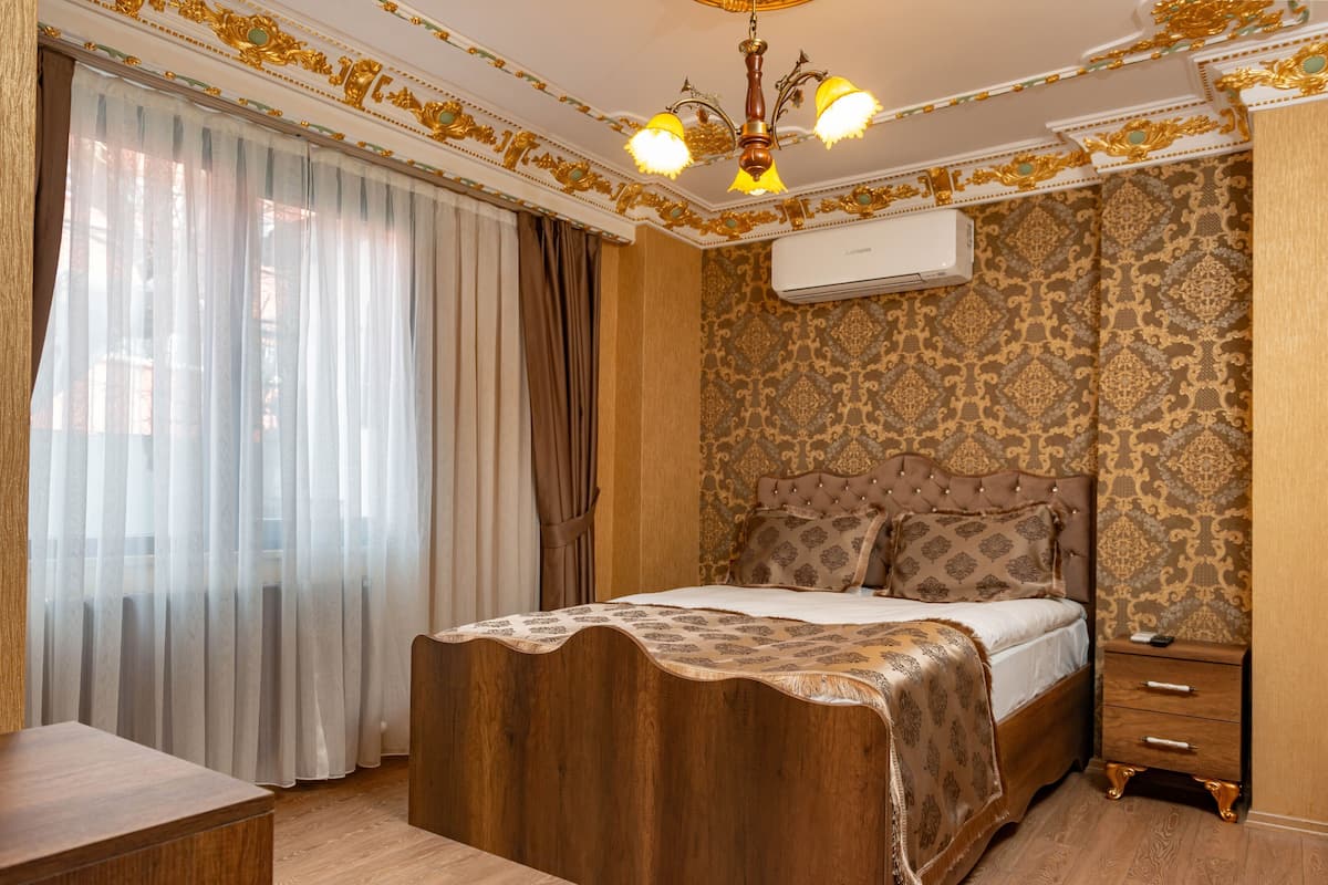 A bedroom with a large bed, a wooden headboard, a nightstand, and a chandelier.