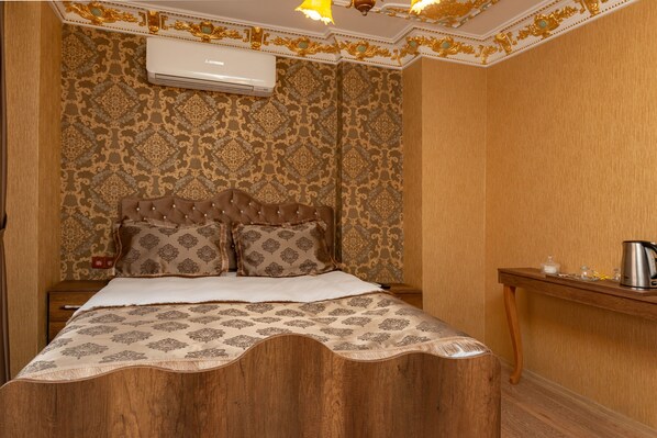 A room with a bed, a nightstand, a wooden table, and an air conditioning unit. - The Ottoman Pansiyon (Istanbul)