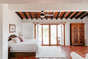 A bedroom with a bed, a wooden wardrobe, and a view through a glass door. - Private Beach- Amazing Surf- Pool -Staff - Gated Home- Suburban & Chef Available (Punta Mita)