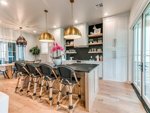 Una cocina moderna con una isla central, sillas de mimbre negro e iluminación colgante.