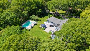 An aerial view of a residential property with a swimming pool, a patio, and a house.