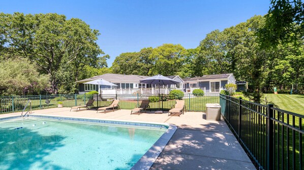 A residential property with a swimming pool, outdoor seating, and a fenced yard.